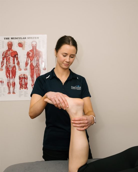 Physiotherapist assessing a patient’s swollen ankle while the patient is lyingon a treatment table.