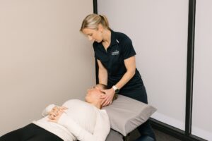 Physio assessing neck movement while patient lying